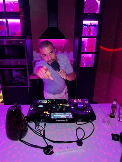 Austin Ventour behind a controller under pink light, microphone in hand, pointing at the camera