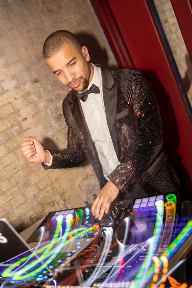Austin Ventour in a sequinned dinner jacket and bow tie at the decks, light trails across the controller